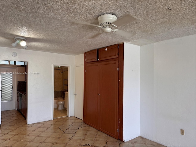 unfurnished bedroom with a textured ceiling, a closet, ensuite bath, and ceiling fan