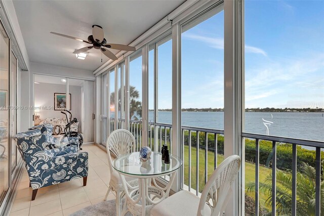 sunroom with a water view and ceiling fan