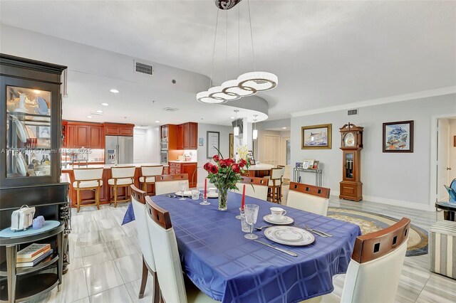 kitchen featuring stainless steel refrigerator, a center island, ornamental molding, a kitchen bar, and decorative light fixtures