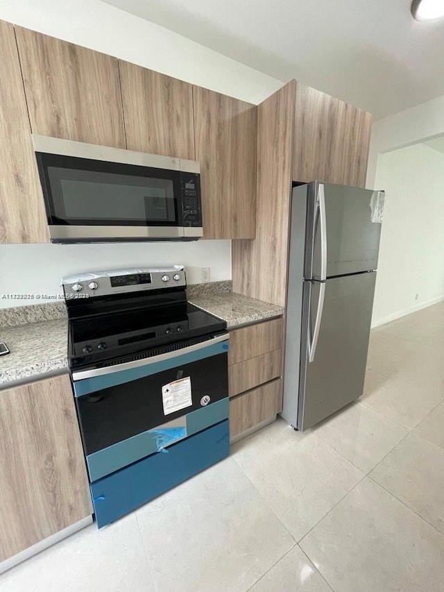 kitchen with light tile patterned floors and stainless steel appliances