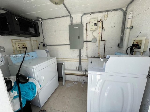 washroom with electric panel, washing machine and dryer, and light tile patterned floors