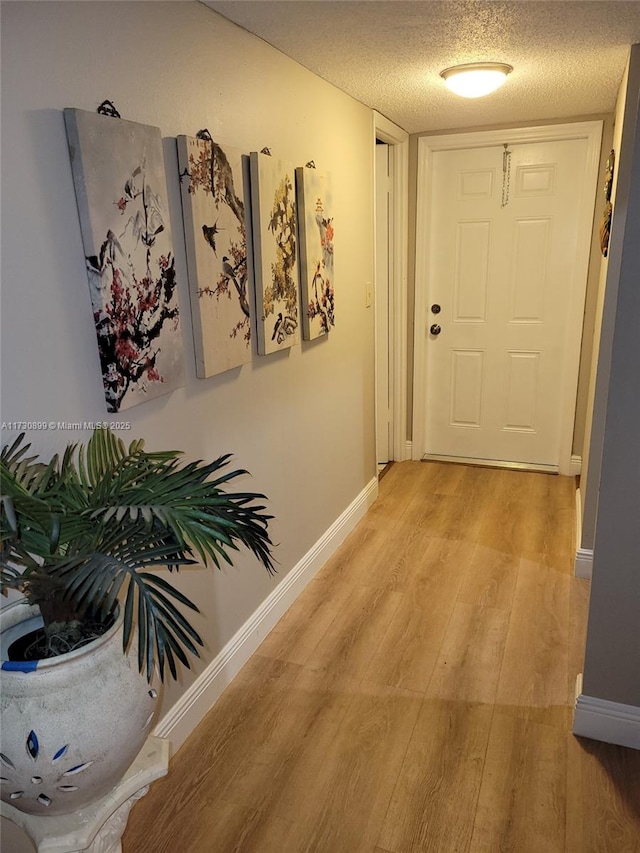 hallway featuring light hardwood / wood-style flooring and a textured ceiling