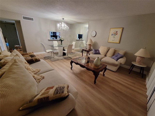 living room featuring a notable chandelier, light hardwood / wood-style flooring, and a textured ceiling