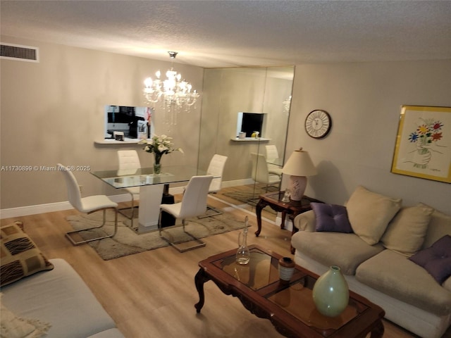 living room featuring light hardwood / wood-style floors, a textured ceiling, and a chandelier