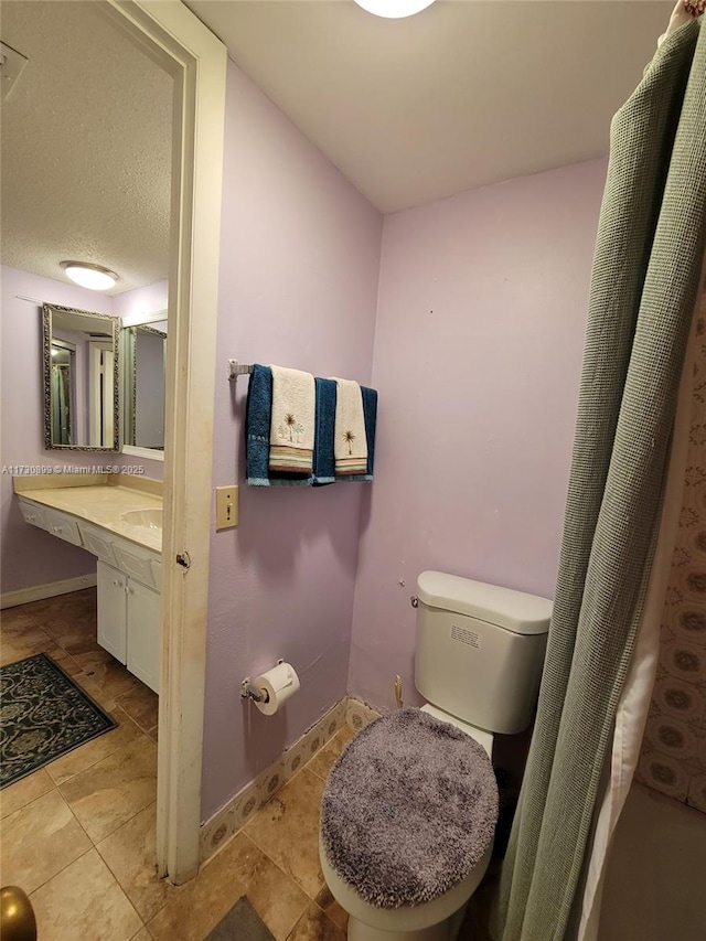 bathroom featuring vanity, toilet, and a textured ceiling