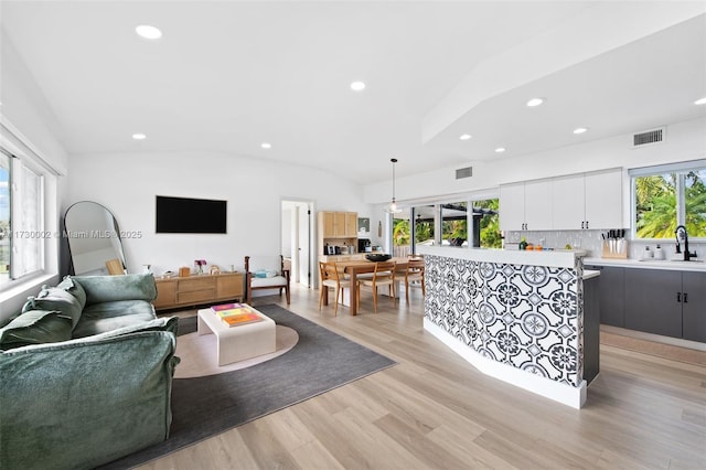 living room featuring light wood-type flooring, sink, and lofted ceiling