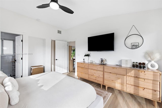 bedroom featuring light hardwood / wood-style flooring, connected bathroom, vaulted ceiling, and ceiling fan