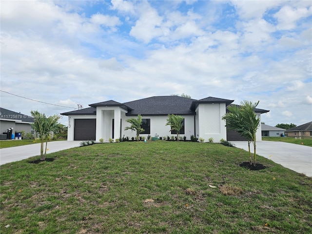 prairie-style home featuring a garage, stucco siding, concrete driveway, and a front yard