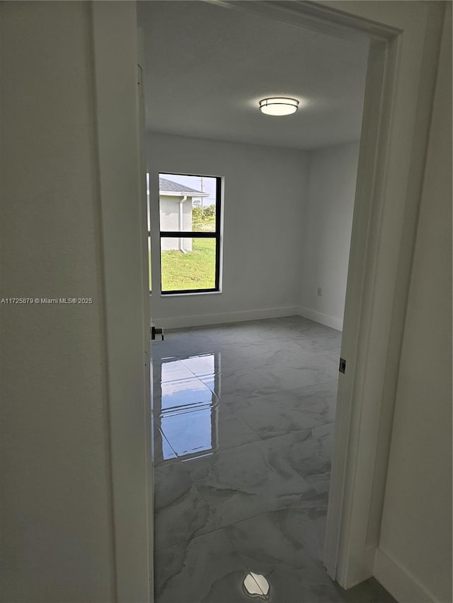 unfurnished room featuring marble finish floor and baseboards