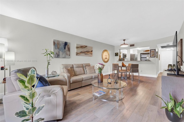 living room featuring visible vents, baseboards, and wood-type flooring