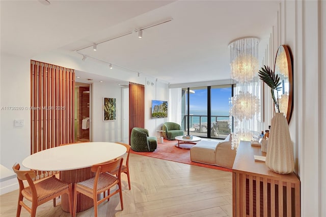 dining space with a water view, floor to ceiling windows, and light parquet flooring