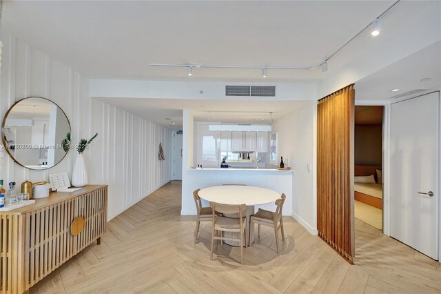 dining space with light parquet floors and track lighting