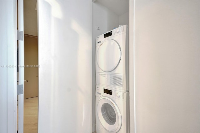 clothes washing area with stacked washer / dryer and light hardwood / wood-style flooring