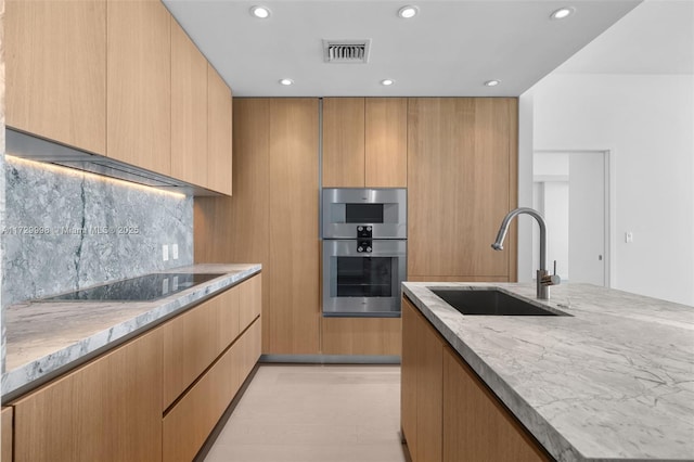 kitchen with light stone countertops, black electric stovetop, decorative backsplash, sink, and double oven