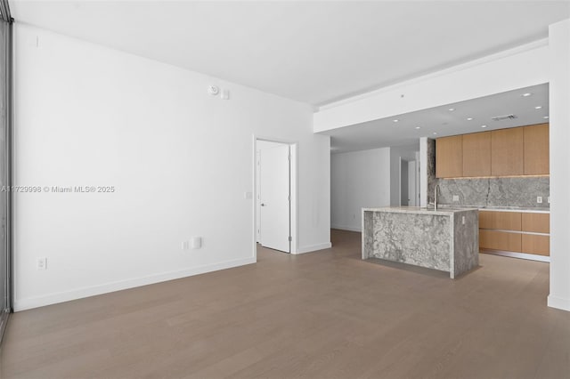 unfurnished living room featuring wood-type flooring and sink