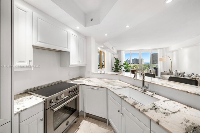 kitchen with electric stove, sink, a kitchen breakfast bar, white cabinets, and kitchen peninsula