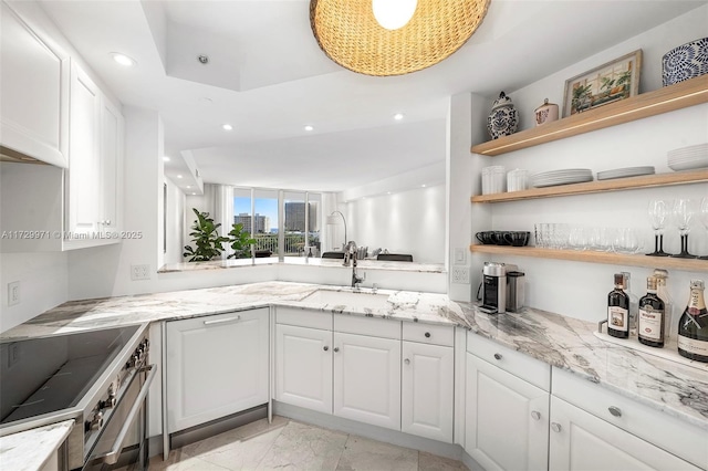 kitchen featuring white cabinetry, sink, stainless steel stove, and light stone counters