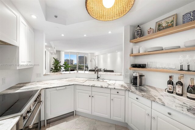 kitchen featuring pendant lighting, stove, light stone counters, white cabinets, and kitchen peninsula