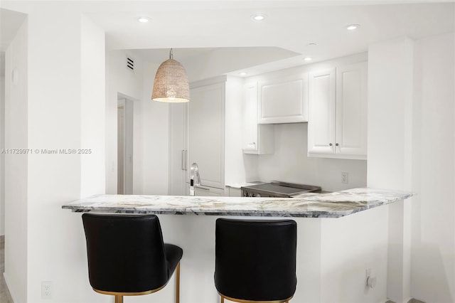 kitchen with white cabinets, light stone countertops, and a breakfast bar area