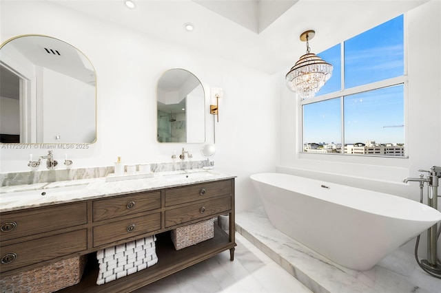 full bath featuring a soaking tub, an inviting chandelier, a sink, and double vanity