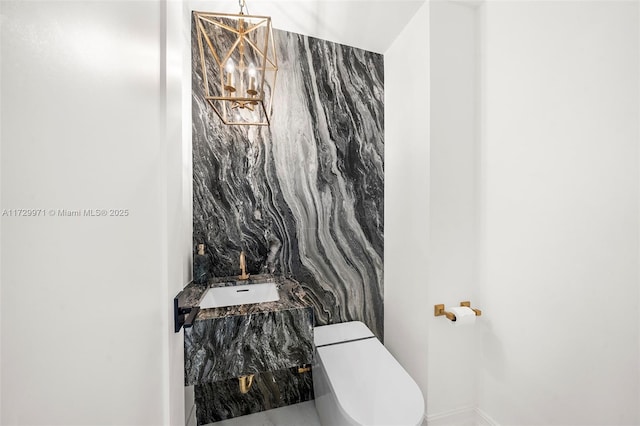 bathroom featuring an inviting chandelier, sink, and toilet