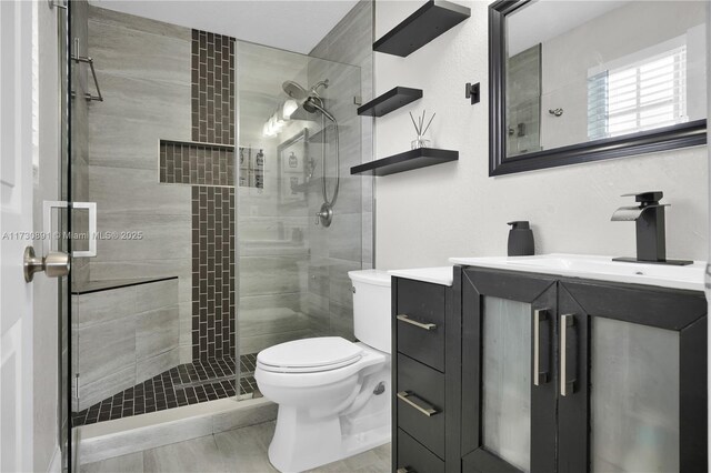 bathroom featuring vanity, toilet, and a shower with shower door