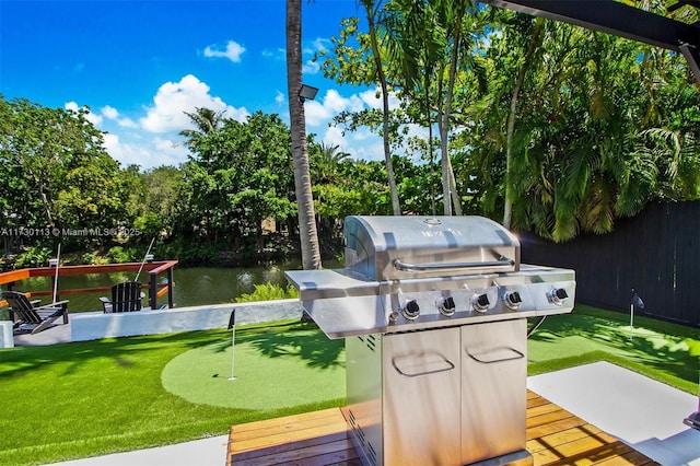 exterior space with a water view, a grill, and fence