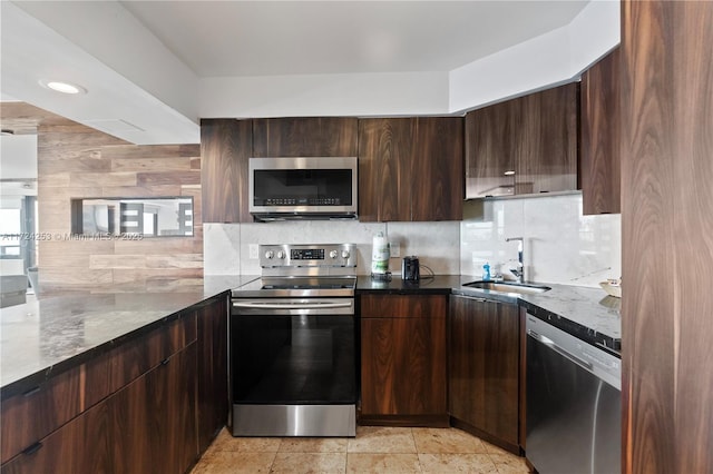 kitchen with sink, appliances with stainless steel finishes, dark stone countertops, dark brown cabinets, and decorative backsplash