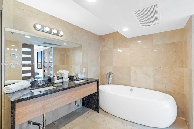 bathroom with a bath, sink, and tile walls