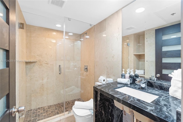 bathroom with a shower with door, sink, and toilet