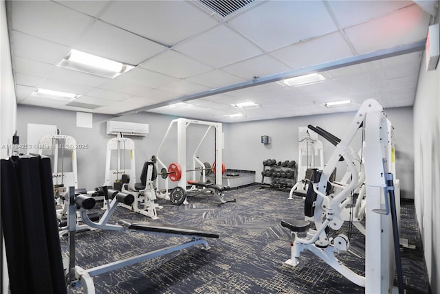 gym featuring a paneled ceiling and a wall unit AC