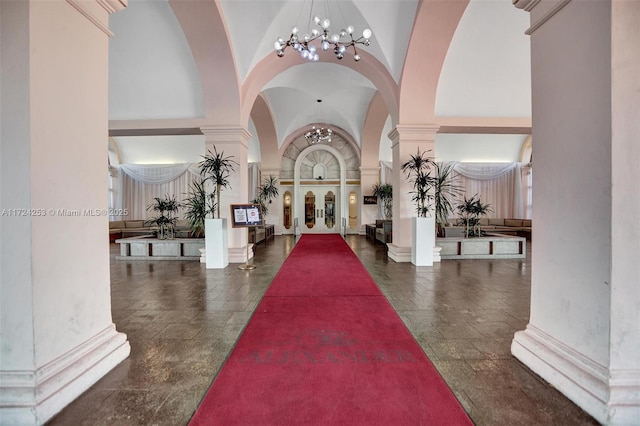 entrance foyer with high vaulted ceiling, a chandelier, and ornate columns