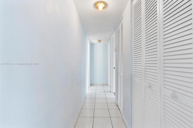 hall featuring light tile patterned floors and a textured ceiling