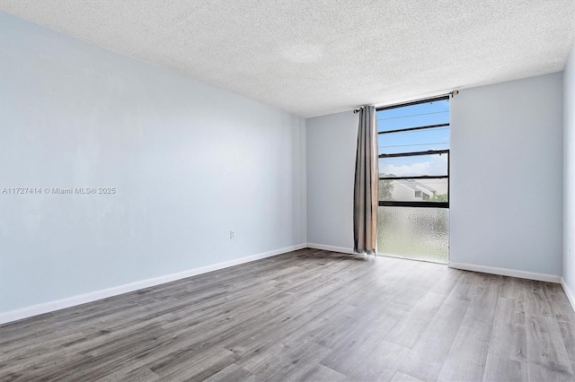 spare room featuring wood-type flooring and a textured ceiling