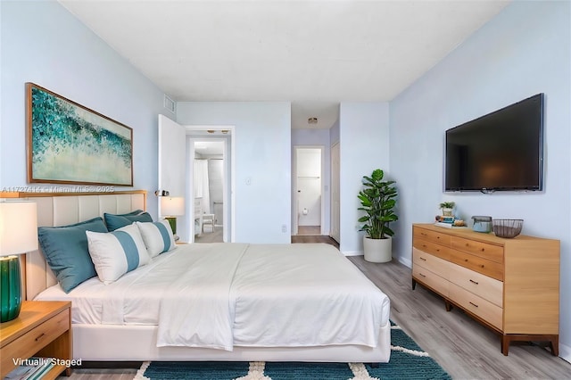 bedroom with ensuite bath and light hardwood / wood-style flooring