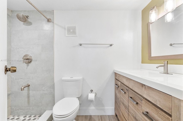 bathroom with vanity, wood-type flooring, a tile shower, and toilet