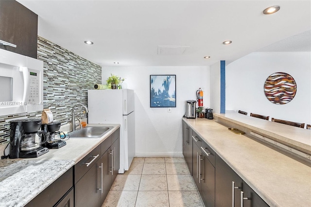 kitchen featuring light tile patterned flooring, sink, decorative backsplash, dark brown cabinets, and white appliances