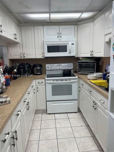 kitchen featuring light tile patterned flooring, white cabinets, and white appliances