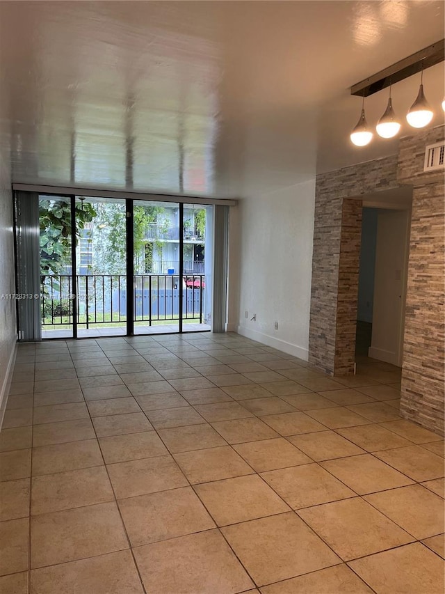 tiled empty room featuring plenty of natural light and floor to ceiling windows