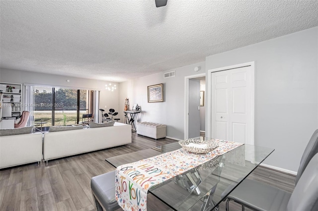 dining area with wood-type flooring and a textured ceiling