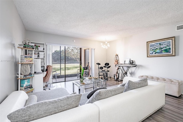 living room featuring a textured ceiling, hardwood / wood-style floors, and a notable chandelier