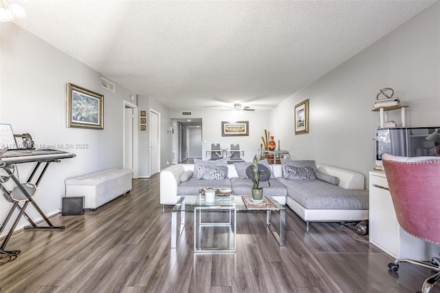 living room with dark wood-type flooring, a textured ceiling, and ceiling fan