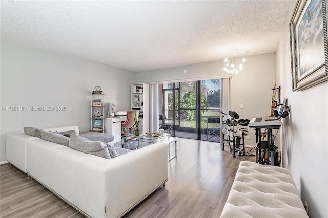 living room featuring light wood-type flooring, an inviting chandelier, and a textured ceiling