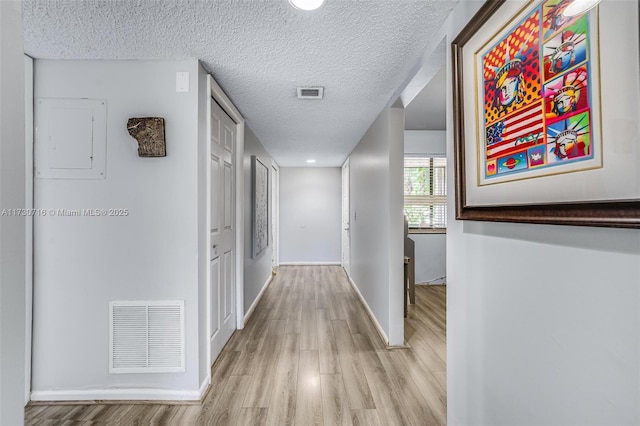 corridor featuring light hardwood / wood-style flooring and a textured ceiling