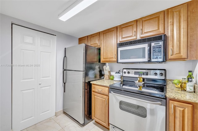 kitchen with light stone countertops, appliances with stainless steel finishes, and light tile patterned floors