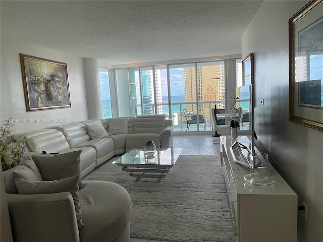 living area with light tile patterned floors, a textured ceiling, and a wall of windows