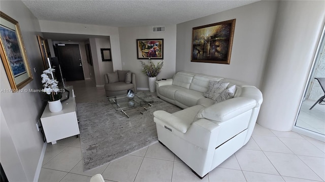 living area with light tile patterned floors, baseboards, visible vents, and a textured ceiling