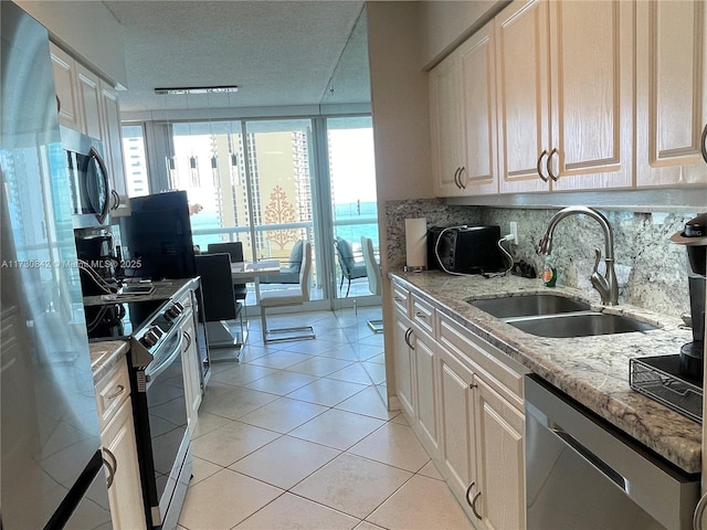 kitchen featuring tasteful backsplash, light stone counters, light tile patterned flooring, stainless steel appliances, and a sink