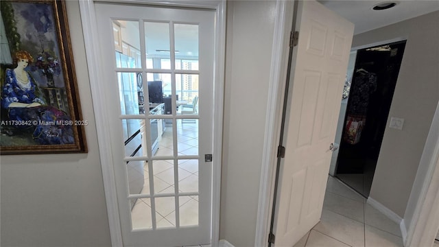 doorway with light tile patterned floors and baseboards