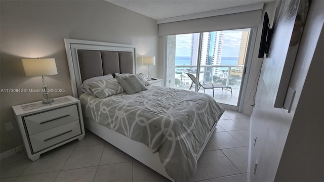 bedroom with a textured ceiling, light tile patterned flooring, and access to outside